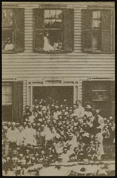 A crowd of people, including Abraham Lincoln, standing in front of the Lincoln Home in 1860. Many are wearing white.