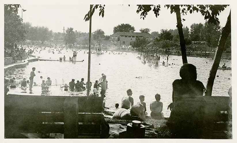 Black-and-white photo of people swimming in a large outdoor pool or lake