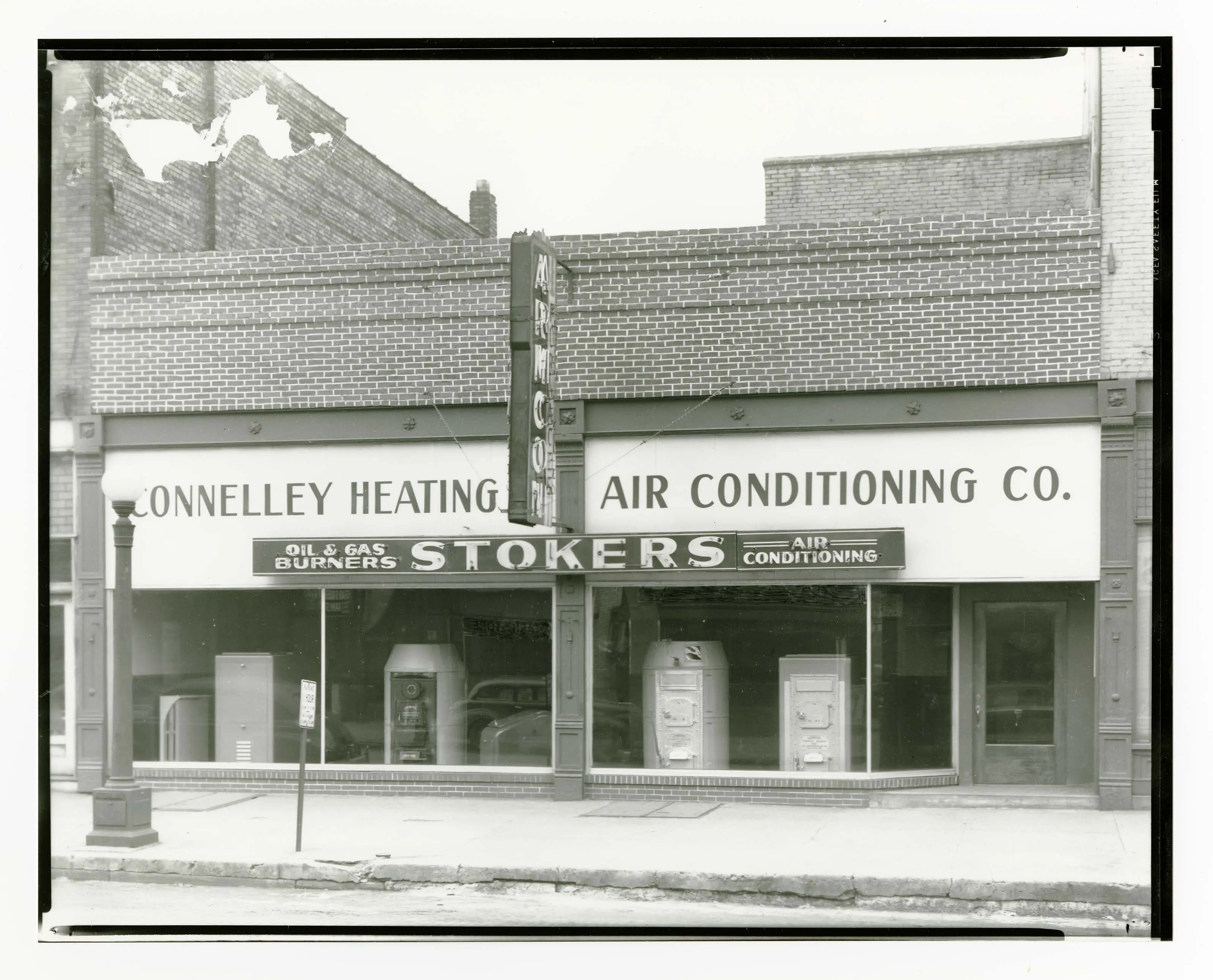 Black-and-white photo of the front of a store. A sign says, "Connelley Heating & Air Conditioning Co."
