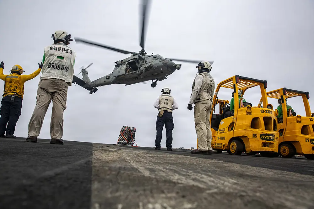 Photo of military personnel waiting as a helicopter lands