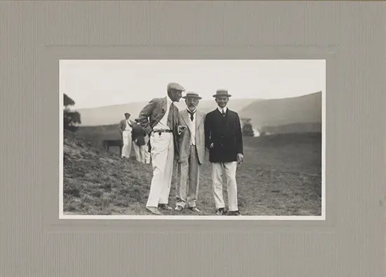 A black-and-white photo of three men on a golf course. Then man in the middle is the elderly Robert Lincoln.