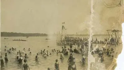Tattered black-and-white photo of people at a pond or lake